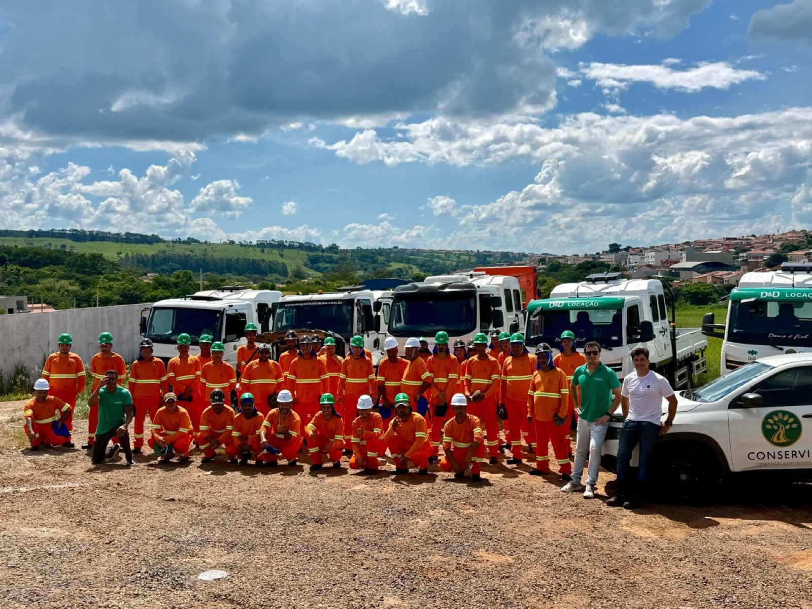 Equipe completa da Conservia reunida diante da frota de caminhões